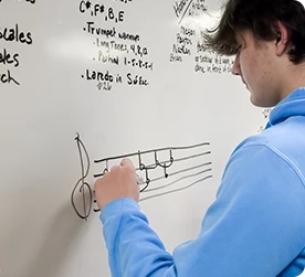 Boy writing music on board