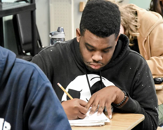 Black student in black sweatshirt writing